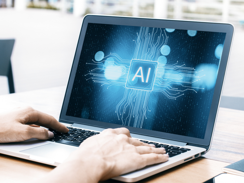 Manos escribiendo en laptop con pantalla mostrando inteligencia artificial aplicada al desarrollo de software