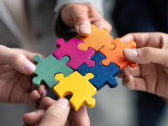 blog-innovacion-abierta-ecosistema-chile Manos colaborando para ensamblar piezas de puzzle de colores vibrantes, representando trabajo en equipo y colaboración en ecosistemas de innovación